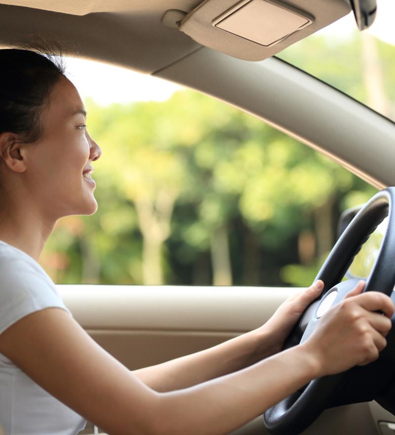 Adolescente asiatique souriant sur le siège du conducteur